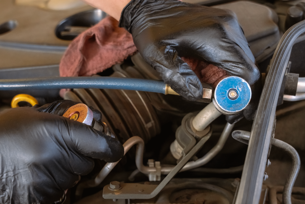 automotive A/C service being performed under the hood of a vehicle