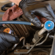 automotive A/C service being performed under the hood of a vehicle